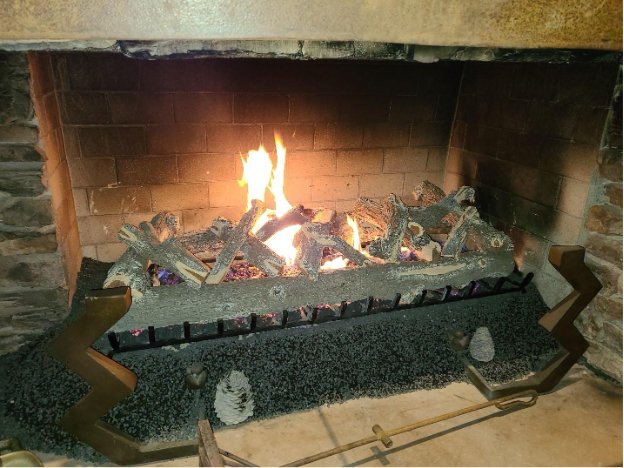 A fireplace with a fire and a couple of peopleAI-generated content may be incorrect.