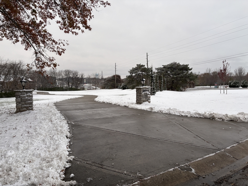 Stone pillar driveway entrance cleared of snow in Grain Valley, MO, serviced by Marrs Lawn and Landscape.