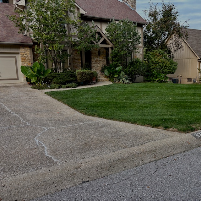 Freshly mowed front yard with clean driveway on a residential home serviced by Marrs Lawn and Landscape in Grain Valley, MO.