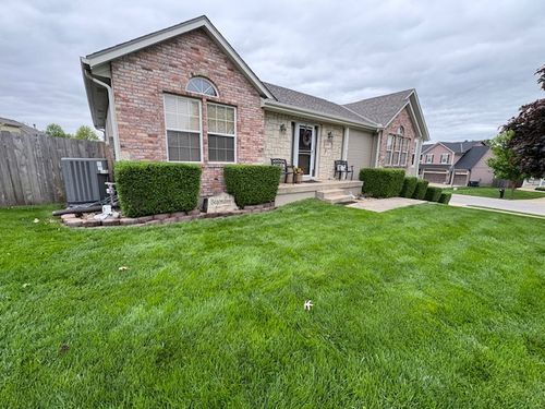 Brick residential home with neatly trimmed shrubs and freshly mowed lawn serviced by Marrs Lawn and Landscape in Grain Valley, MO.