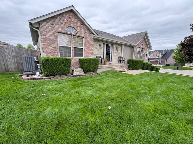 Brick residential home with neatly trimmed shrubs and freshly mowed lawn serviced by Marrs Lawn and Landscape in Grain Valley, MO.