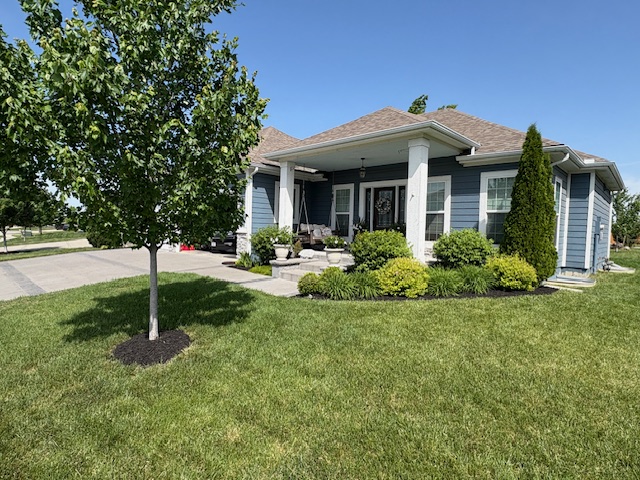 Neatly mowed lawn with trimmed shrubs and landscaped front yard on a residential home serviced by Marrs Lawn and Landscape in Grain Valley, MO.