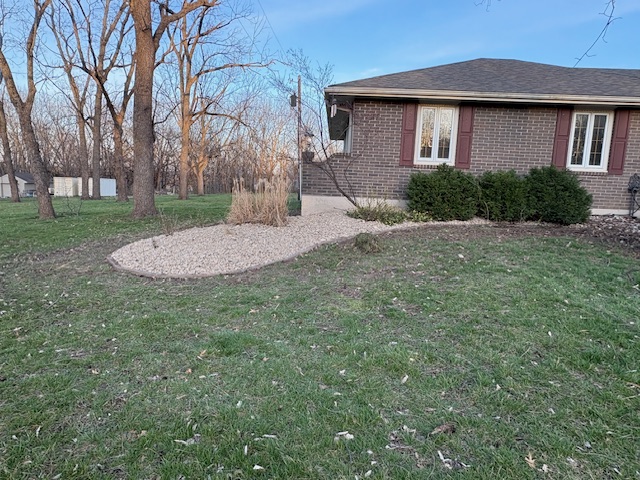 Landscape bed with decorative rock and mulch installed along a brick home in Grain Valley, MO, by Marrs Lawn and Landscape.