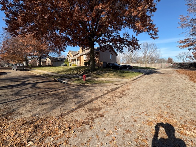 Residential yard with fall leaves along the curb ready for leaf vacuum haul-away by Marrs Lawn and Landscape in Grain Valley, MO