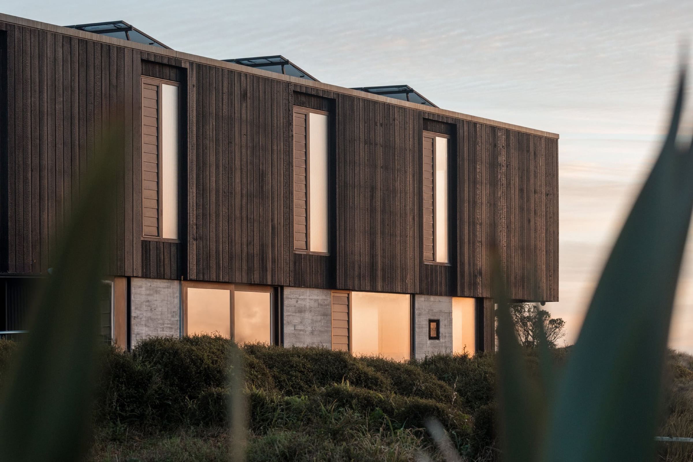 Vertical charred-timber cladding on a coastal home at dusk