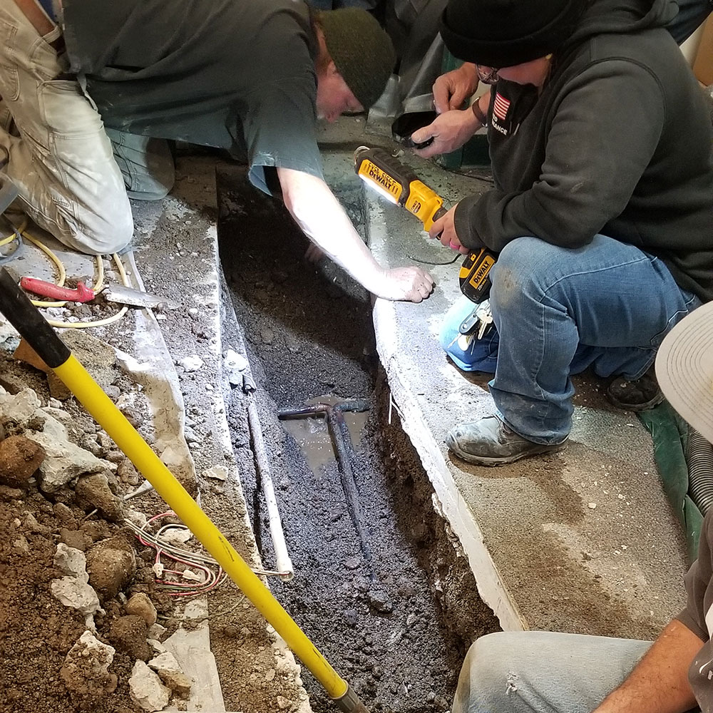 Men working on Pipes under concrete floors