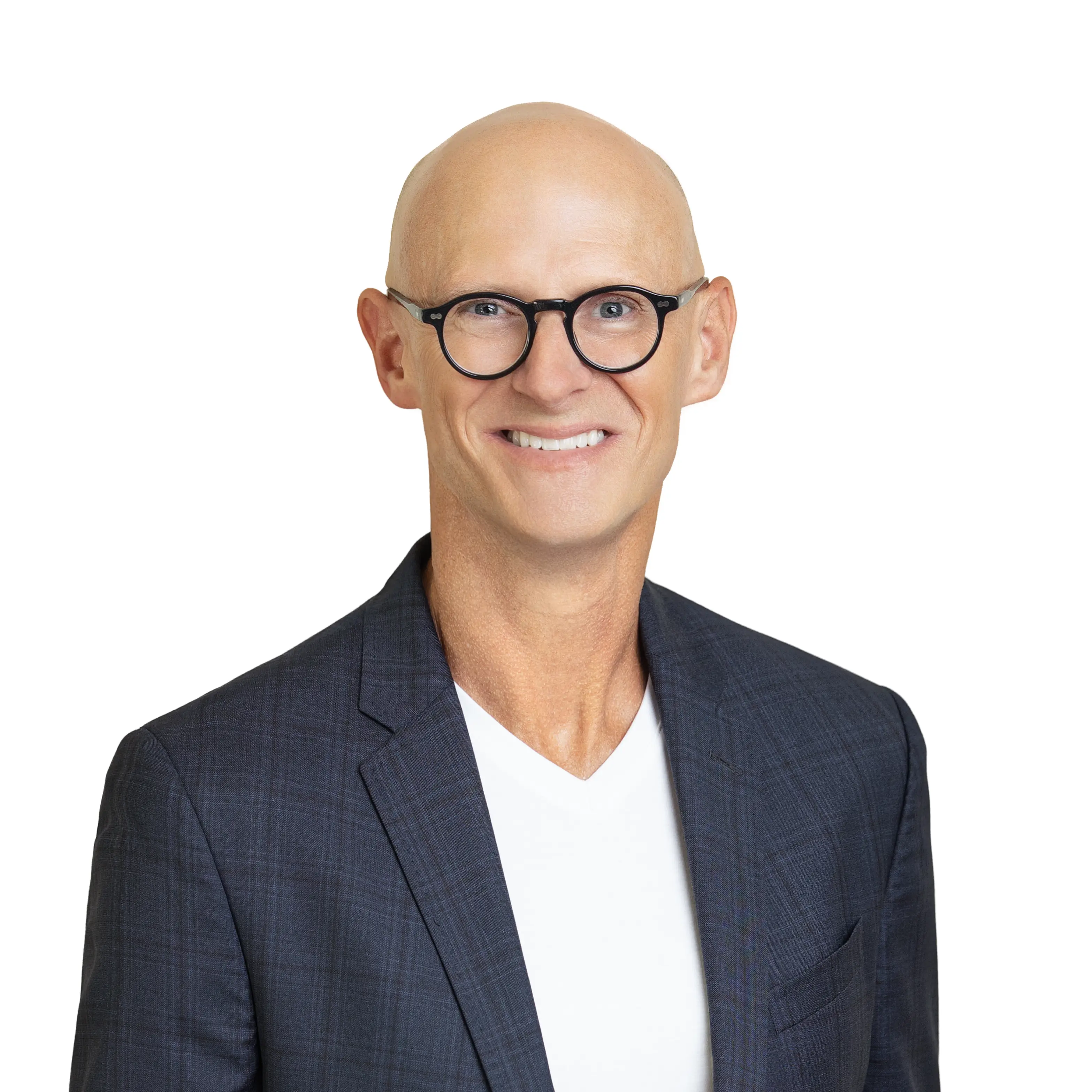 Smiling bald man wearing round black glasses, a dark checkered blazer, and a white V-neck shirt on a white background.