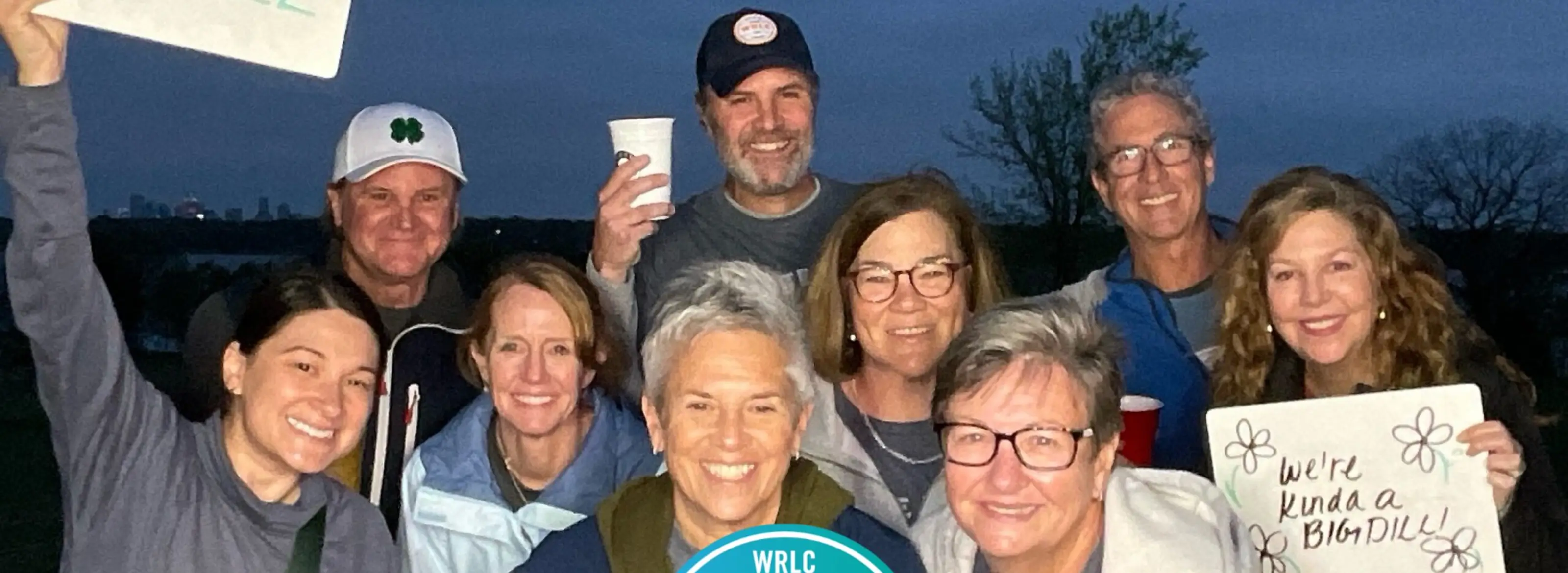Group of eight people smiling outdoors at Celebration White Rock race in Dallas, TX.