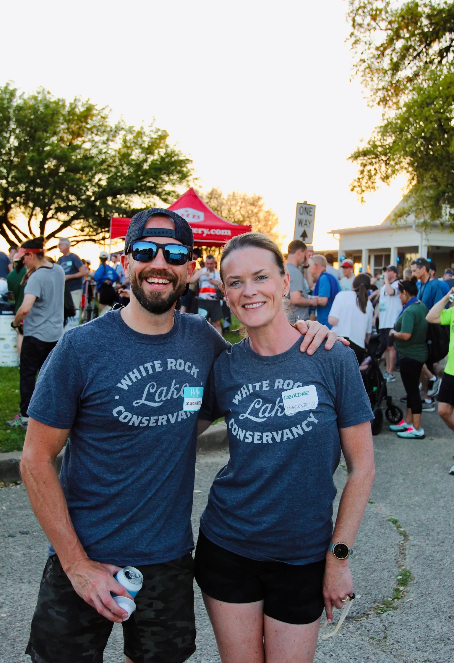 Smiling man and woman wearing matching White Rock Lake Conservancy t-shirts at Celebration White Rock.