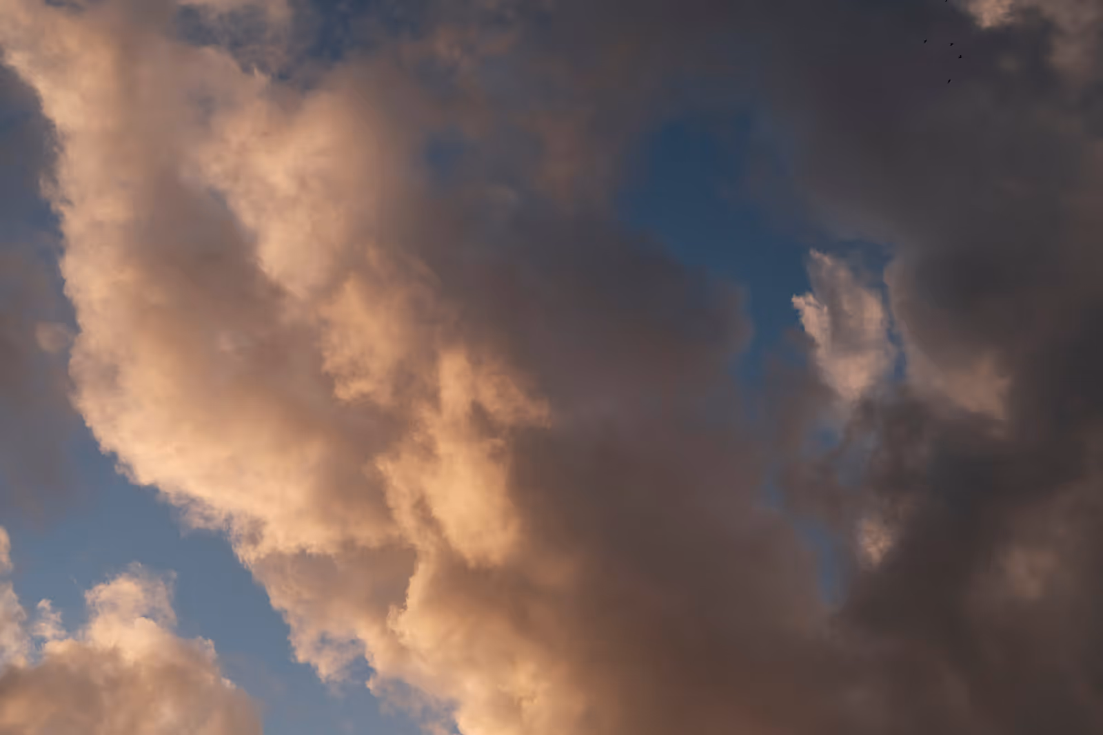 Large clouds illuminated by warm sunlight against a blue sky.