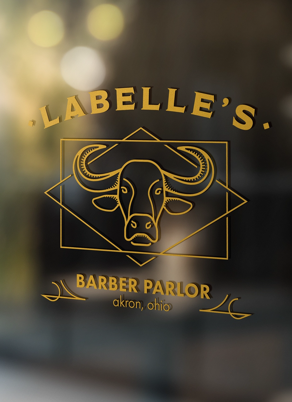 Gold lettering on glass showing 'LABELLE'S BARBER PARLOR akron, ohio' with a stylized buffalo head logo.