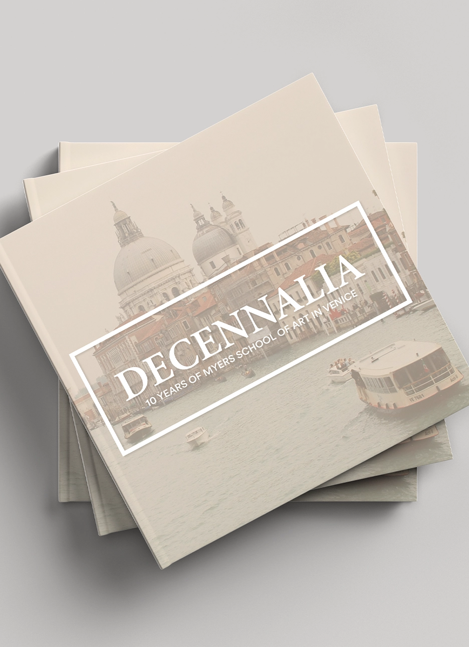 Stack of tan books titled 'DECENNALIA 10 Years of Myers School of Art in Venice' with cover image of Venice buildings and boats on water.