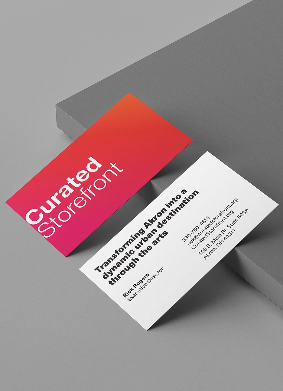 Two business cards, one with 'Curated Storefront' in white text on a red-orange gradient background, the other with contact info for Rick Rogers, Executive Director of Curated Storefront, including phone, email, website, and address in Akron, Ohio.