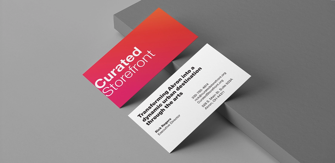 Two business cards, one with 'Curated Storefront' in white text on a red-orange gradient background, the other with contact info for Rick Rogers, Executive Director of Curated Storefront, including phone, email, website, and address in Akron, Ohio.