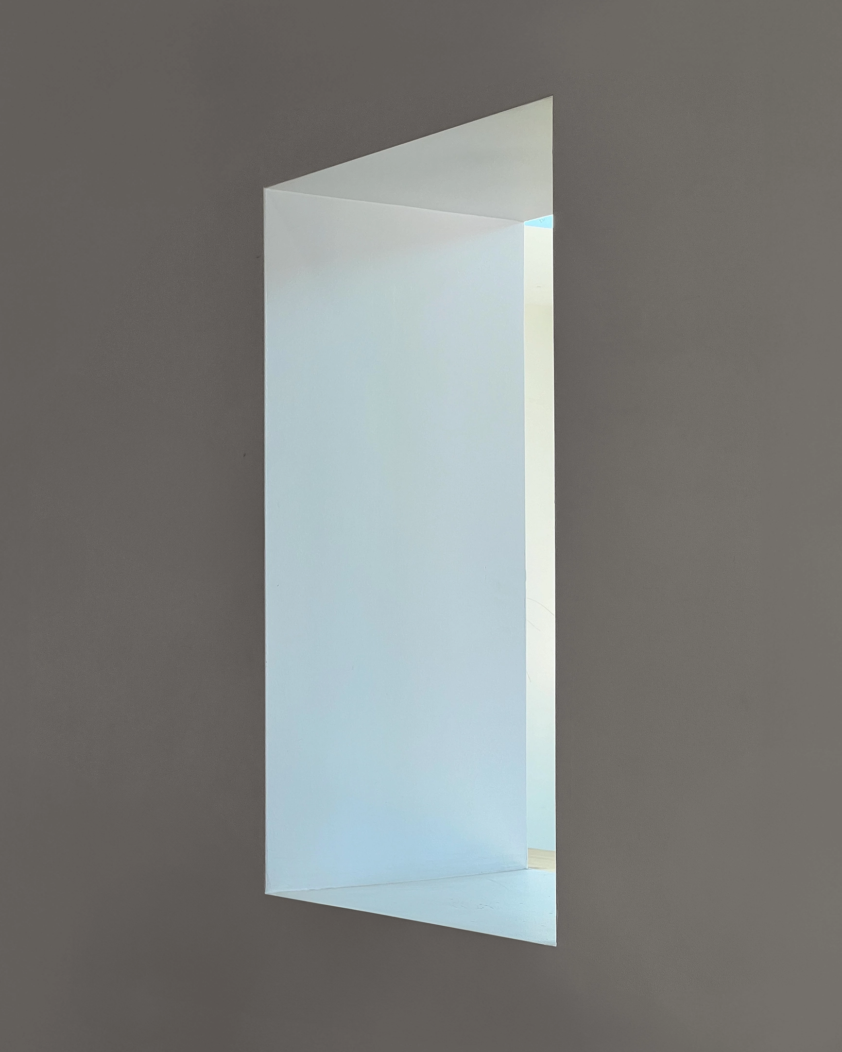 Minimalist rectangular architectural cutout in a wall revealing a softly lit interior space.