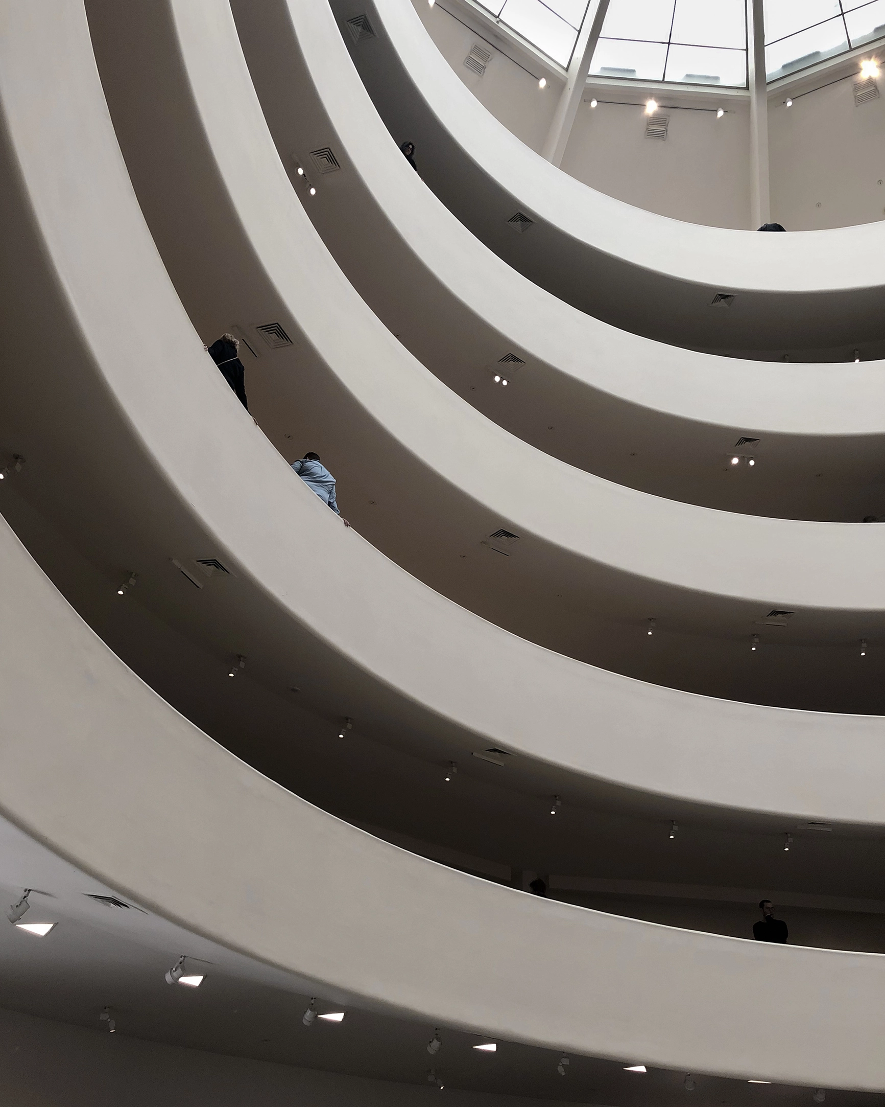 Interior view of Guggenheim curved balconies and skylight ceiling, showing people on different floors.