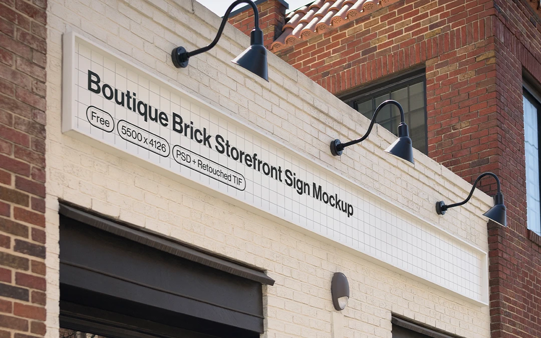 White brick storefront with black framed windows and a rectangular sign under three black gooseneck lights.