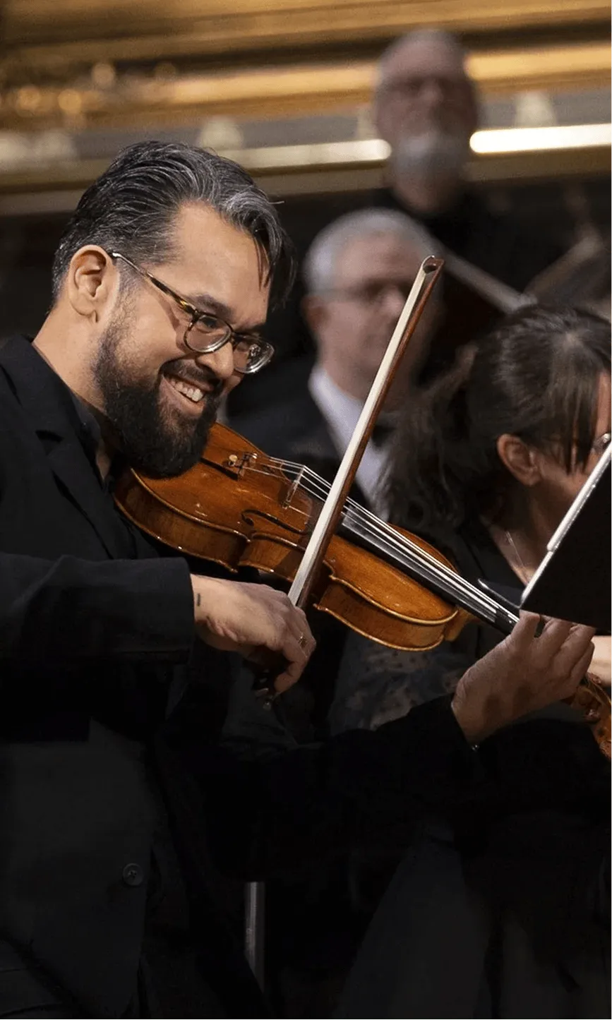 Vijay Gupta performing on violin with an orchestra