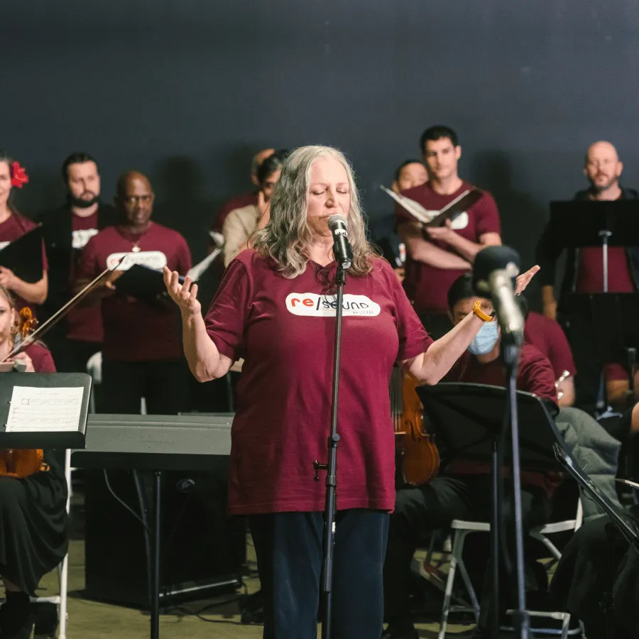 Woman singing with a choir in a performance space