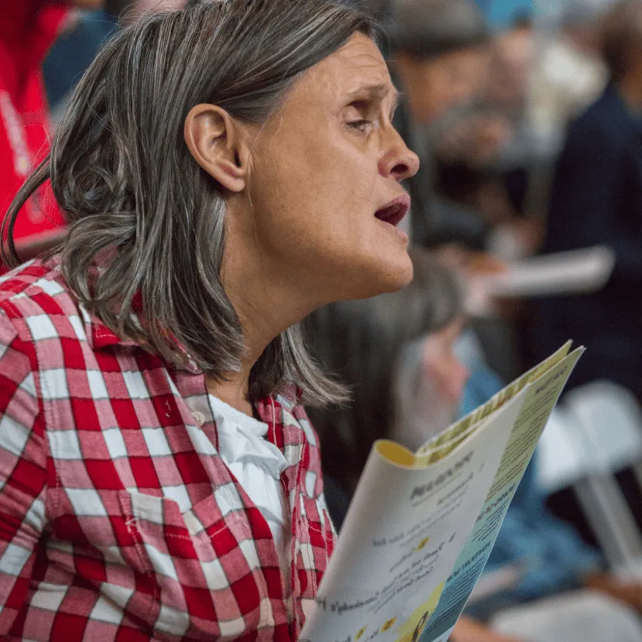 Woman speaking and holding papers at an outdoor event