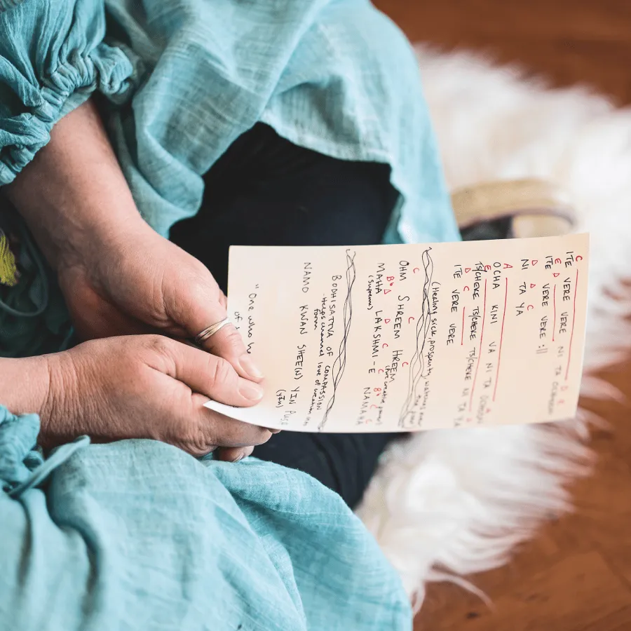 Hands holding a sheet of music while sitting