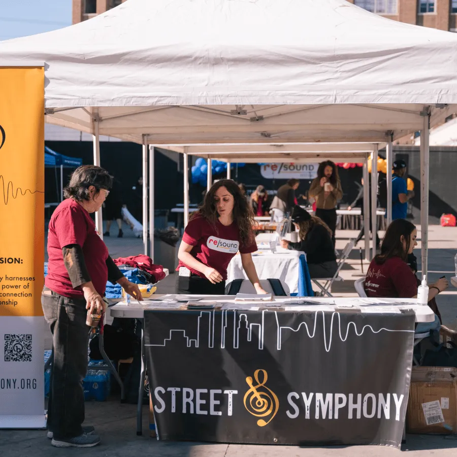Volunteers staffing a Street Symphony booth at an outdoor event