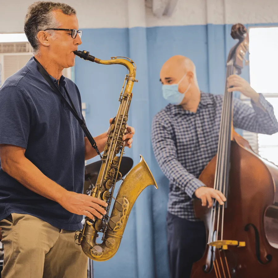 Two musicians playing saxophone and upright bass indoors