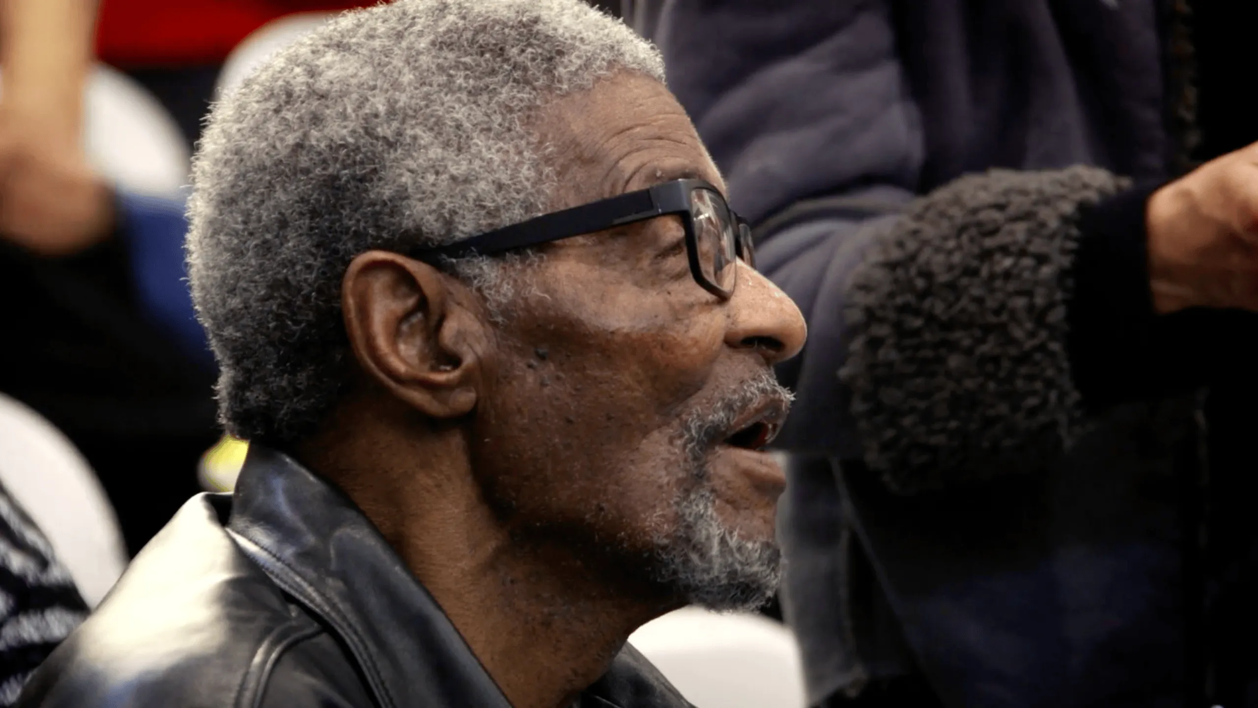 Older man in glasses listening during an event