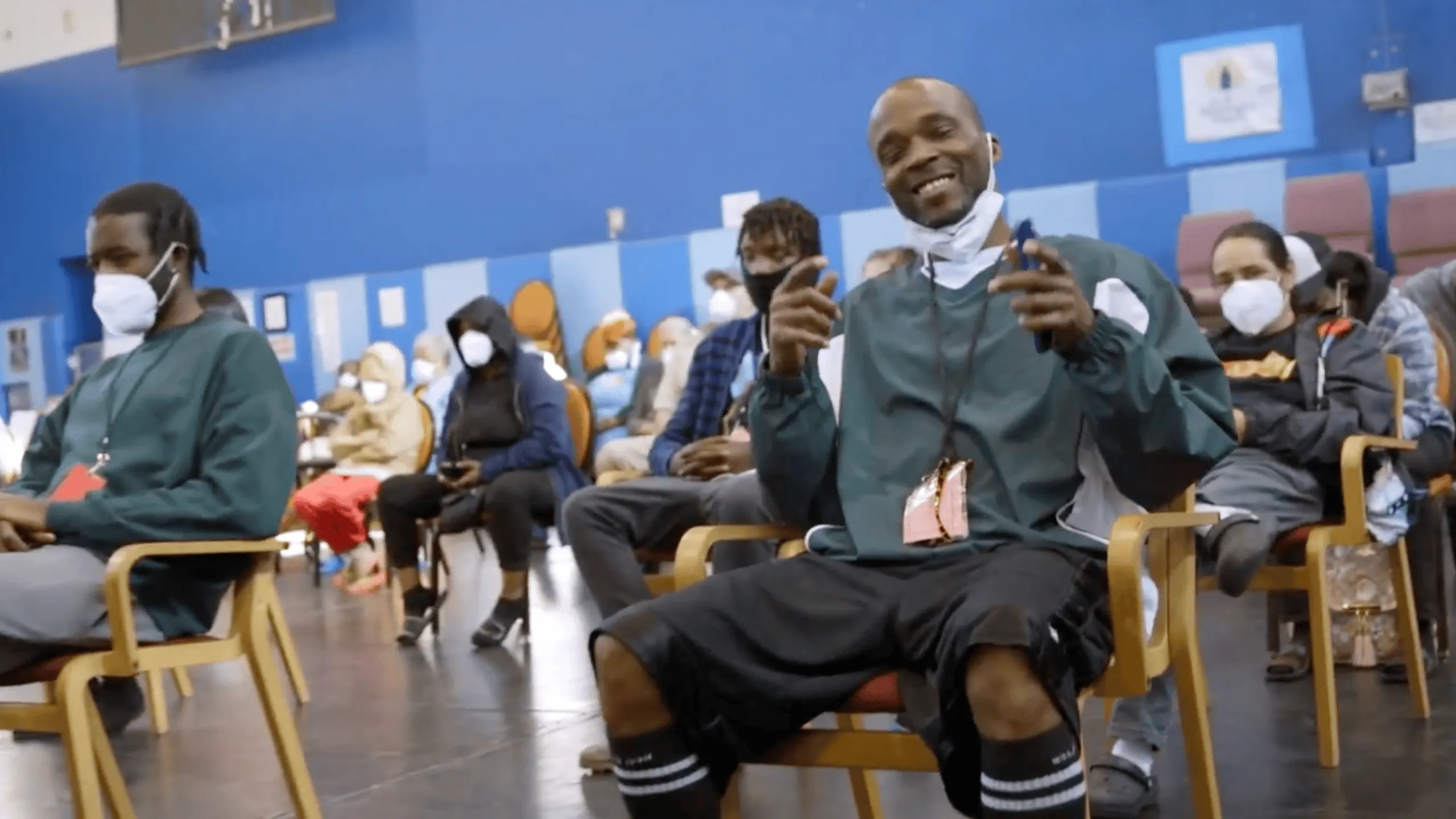 Audience members seated in a community event, some smiling and wearing masks