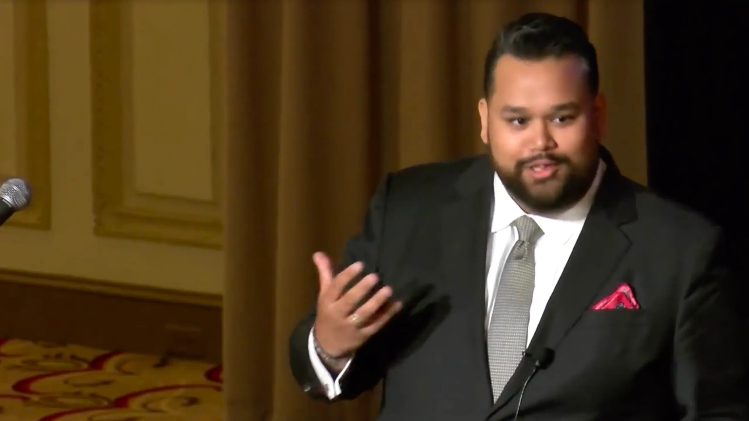 Vijay Gupta speaking into a microphone during a presentation