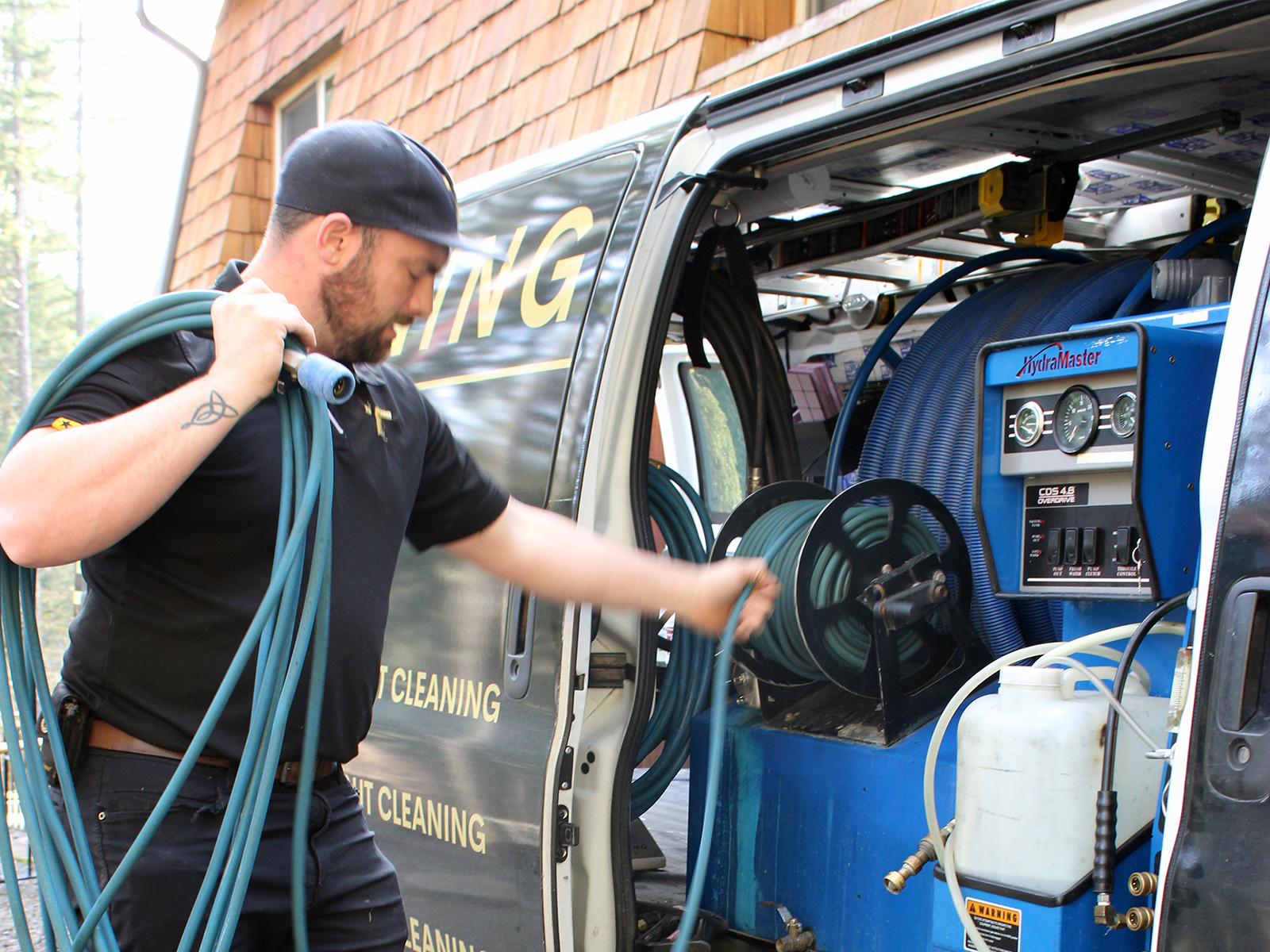 Matt from TEXCO Cleaning loading a hose into a work van stocked with steam cleaning equipment