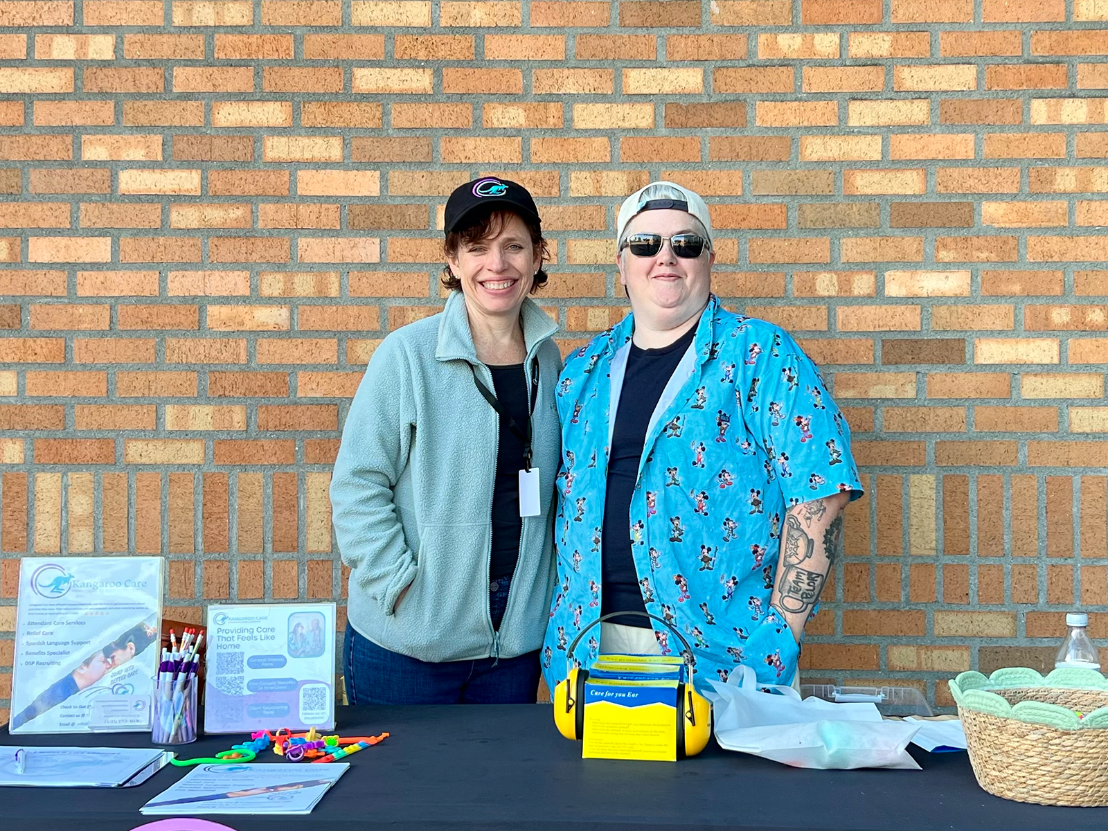 Kangaroo Care staff at a community event table with service flyers and sensory toys on display