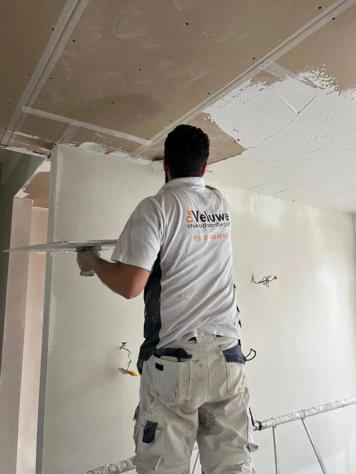 Stukadoorbedrijf van Stukadoors de Veluwe werkt aan plafond stucwerk met truweel in onafgewerkte ruimte voor strakke afwerking