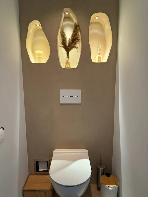 Modern toilet met taupe stucwerk wandafwerking en drie verlichte inbouwnissen voor decoratie