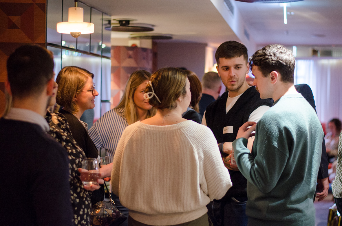 A group of young adults engaged in conversation at an indoor social gathering.
