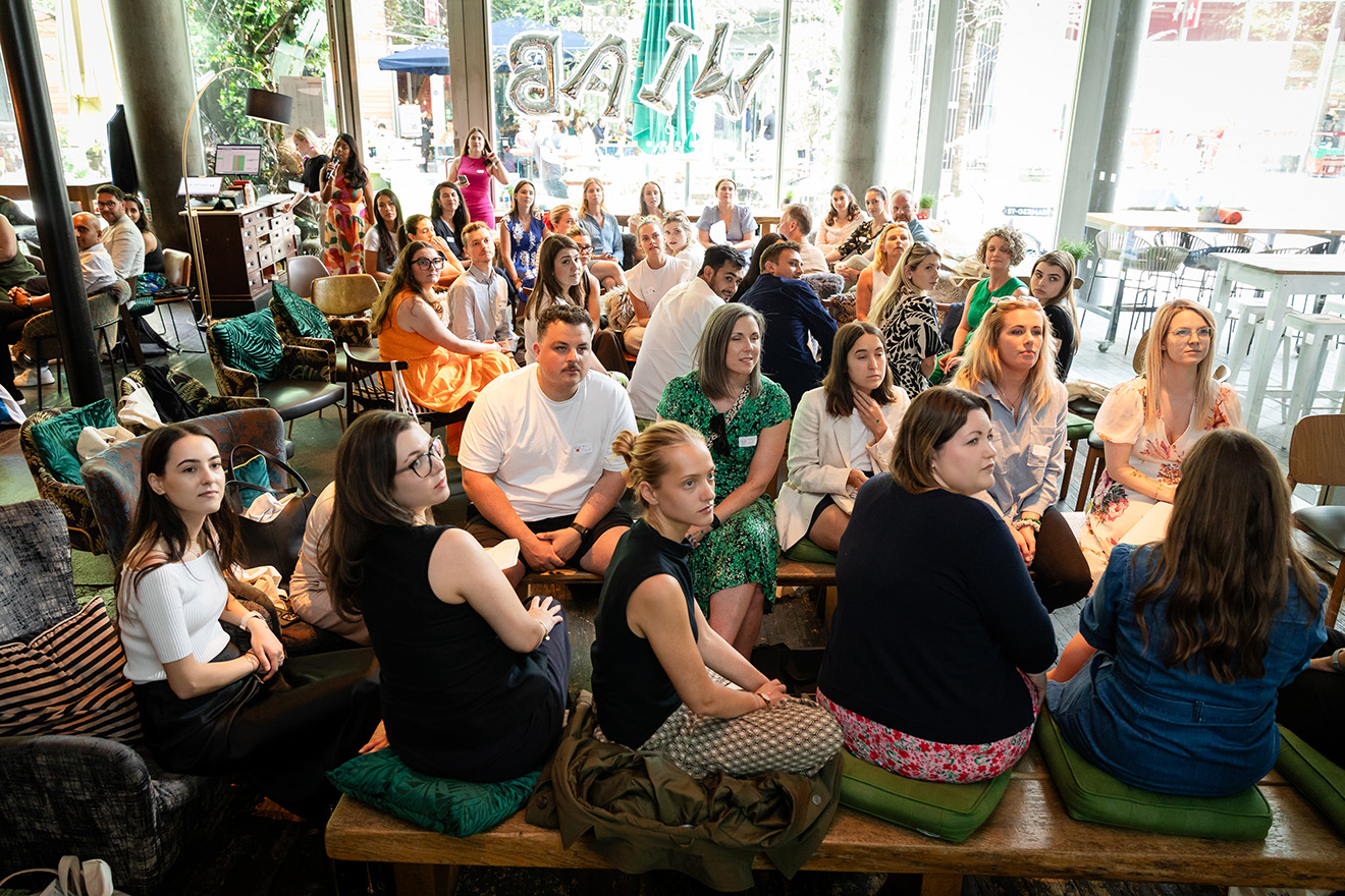 Group of people sitting closely in a room, attentively listening to a speaker at an event.