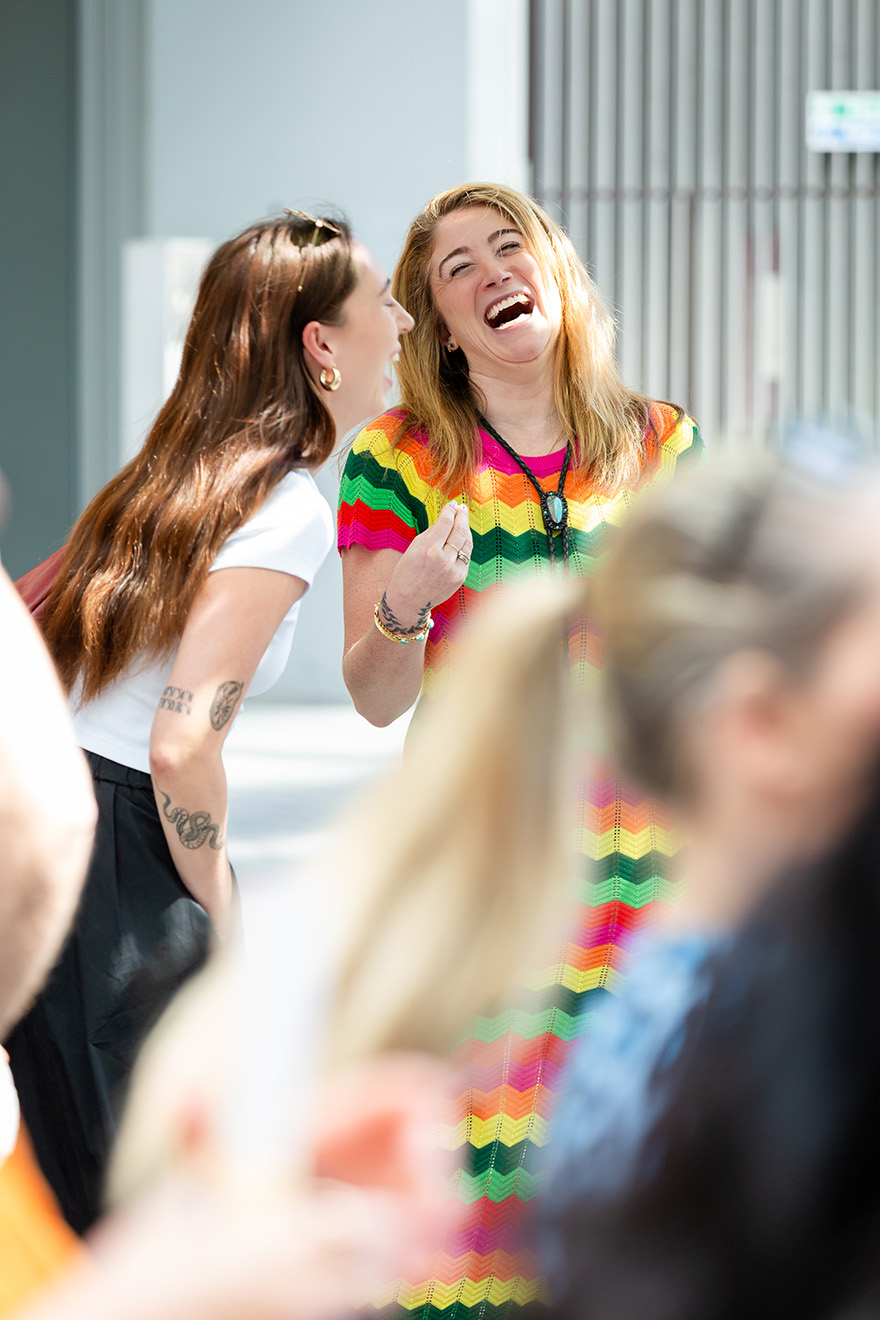 A group of women seated indoors engaged in a discussion, with two women holding microphones.