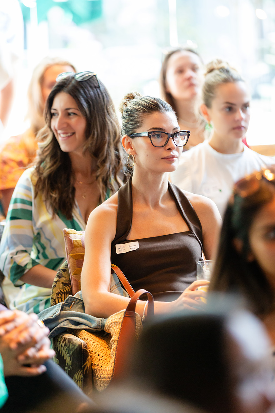 A group of young adults engaged in conversation in a warmly lit indoor space.