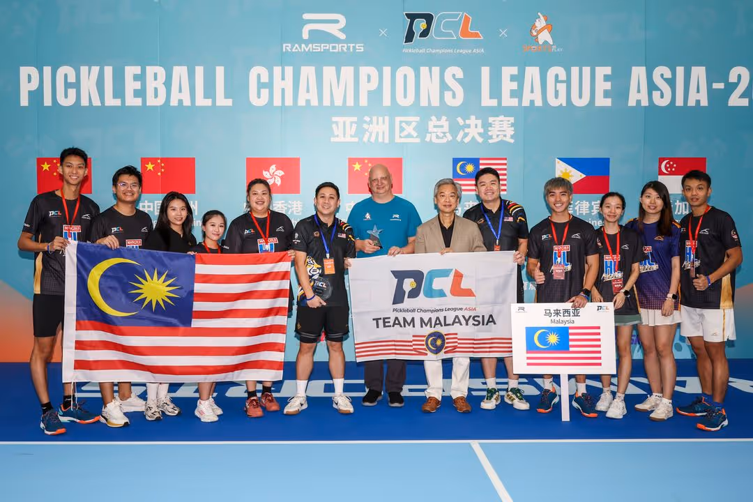 Group photo of Team Malaysia players and officials holding Malaysia flags and banners at the Pickleball Champions League Asia event.