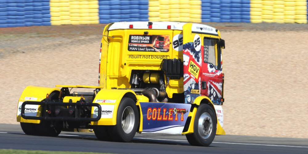 Yellow racing truck with logos driving on a track beside the text 'SOLID X POWER PERFORMANCE PRECISION' on a black background.
