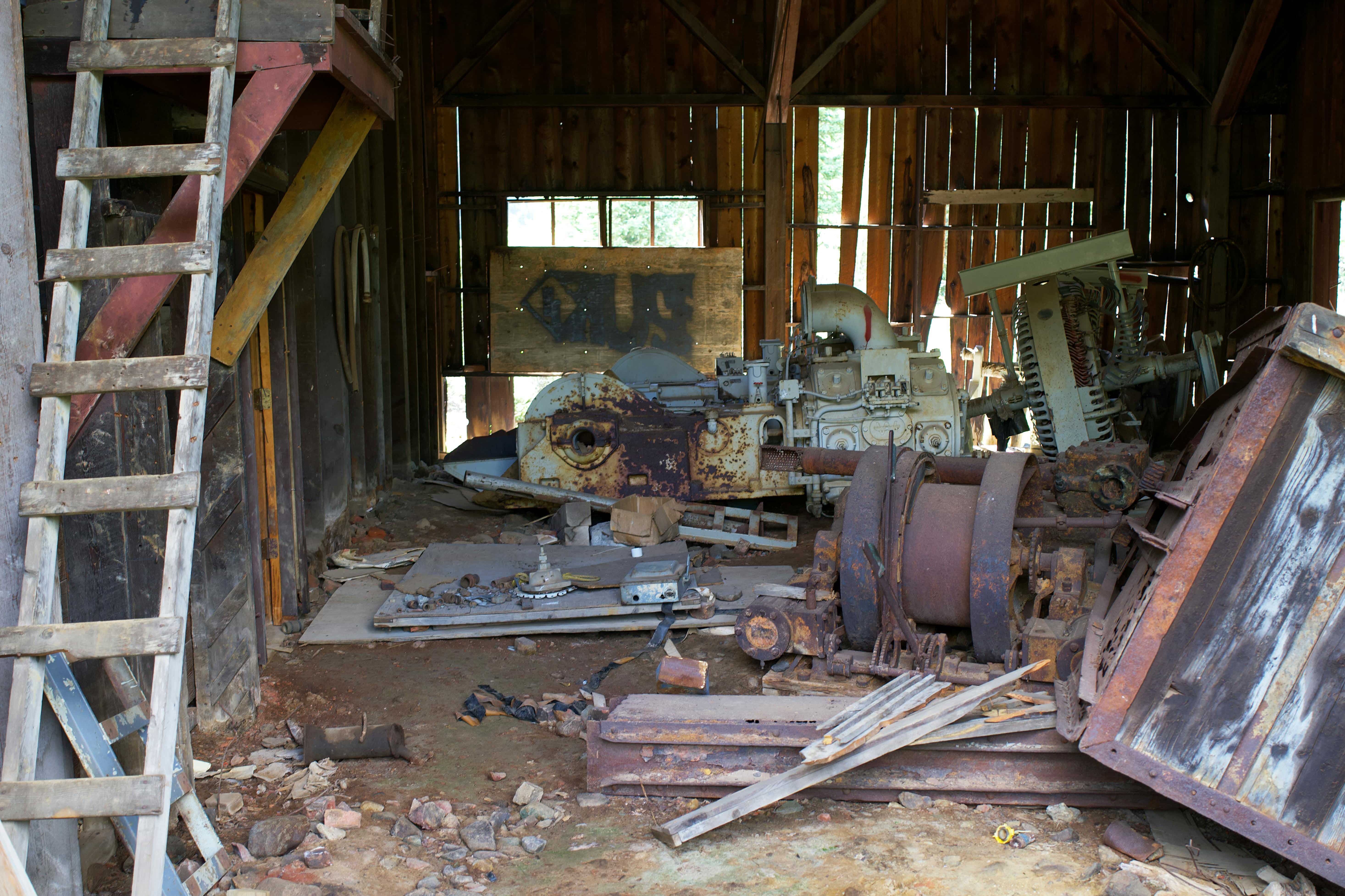 A collection of old, rusty industrial equipment stored in a dimly lit barn, illustrating the concept of aged or surplus inventory.