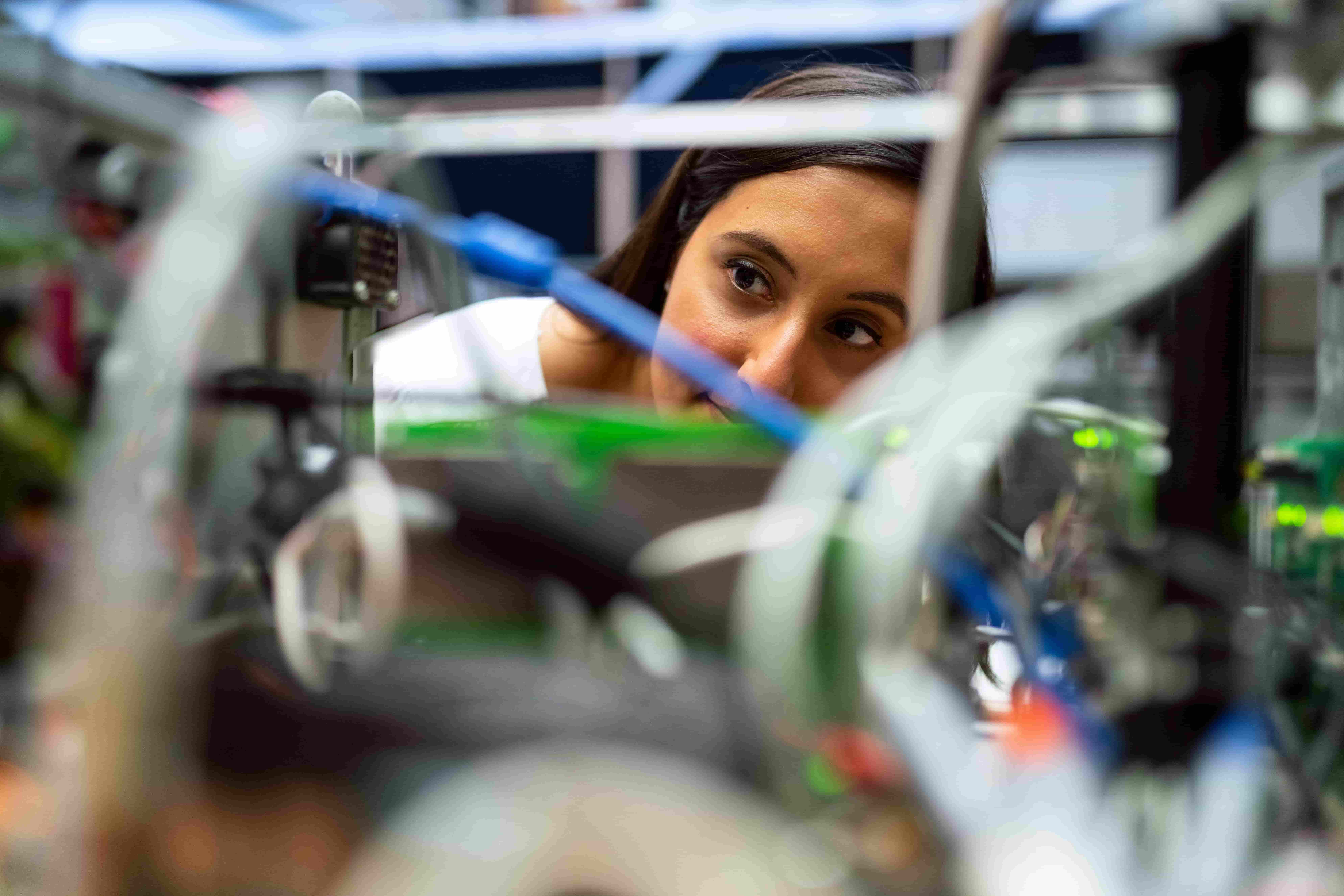 A female engineer inspecting circuit boards and wiring on a production line in an electronics manufacturing facility.
