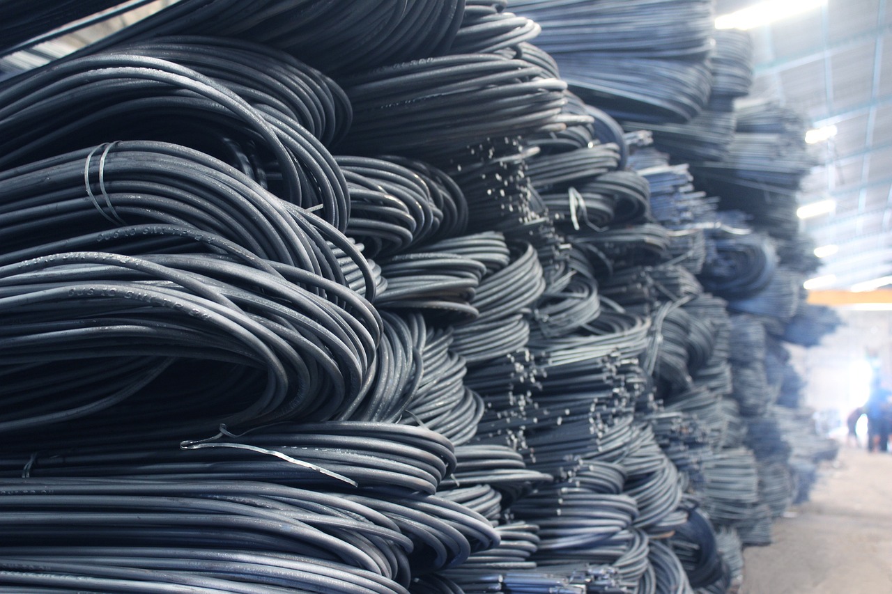 Stacks of coiled steel rods in a warehouse, representing raw material inventory and industrial procurement.