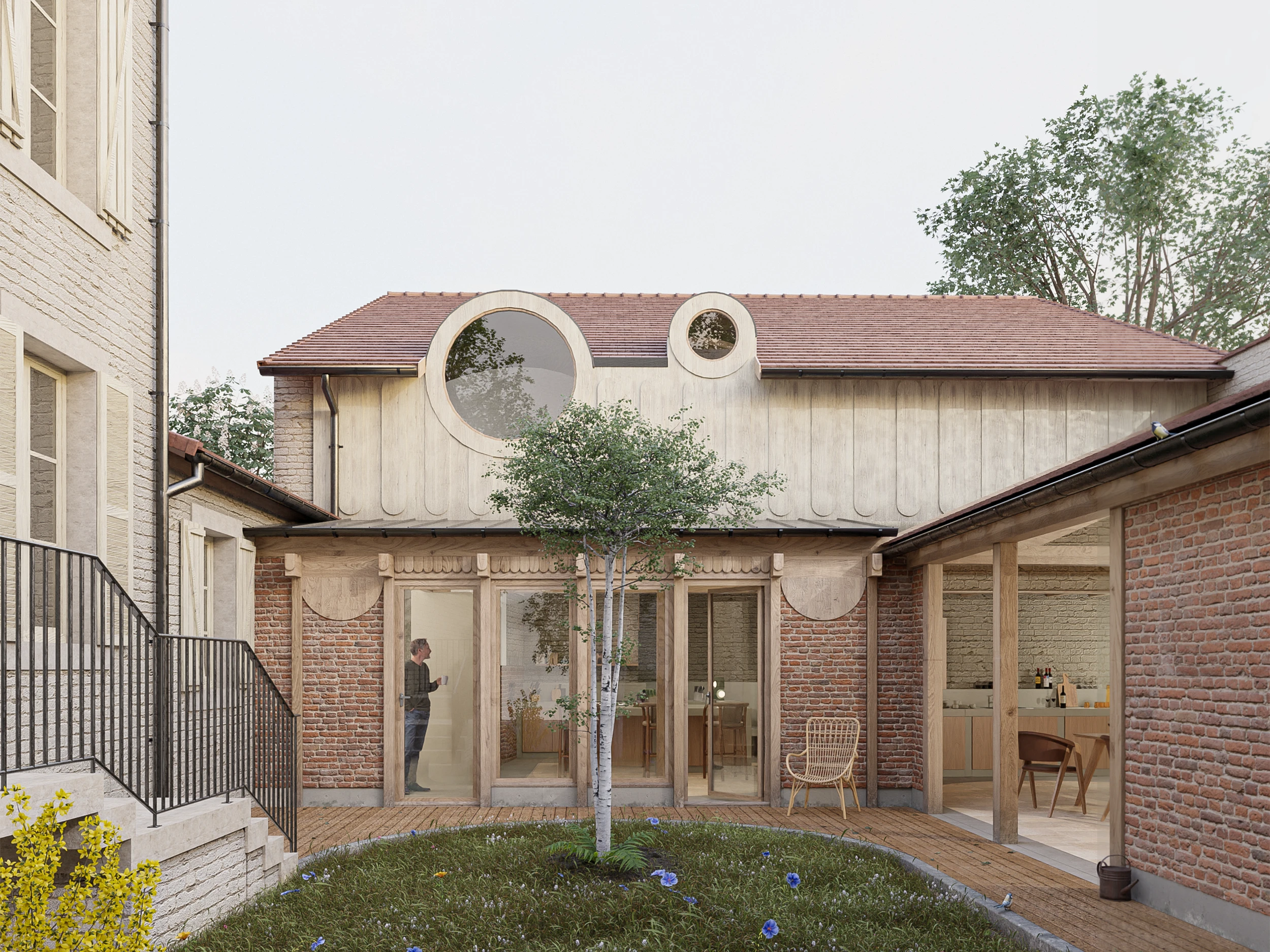 Modern open kitchen and dining area with a wooden interior, oval marble dining table, wooden stools, and large window showing outdoor trees.