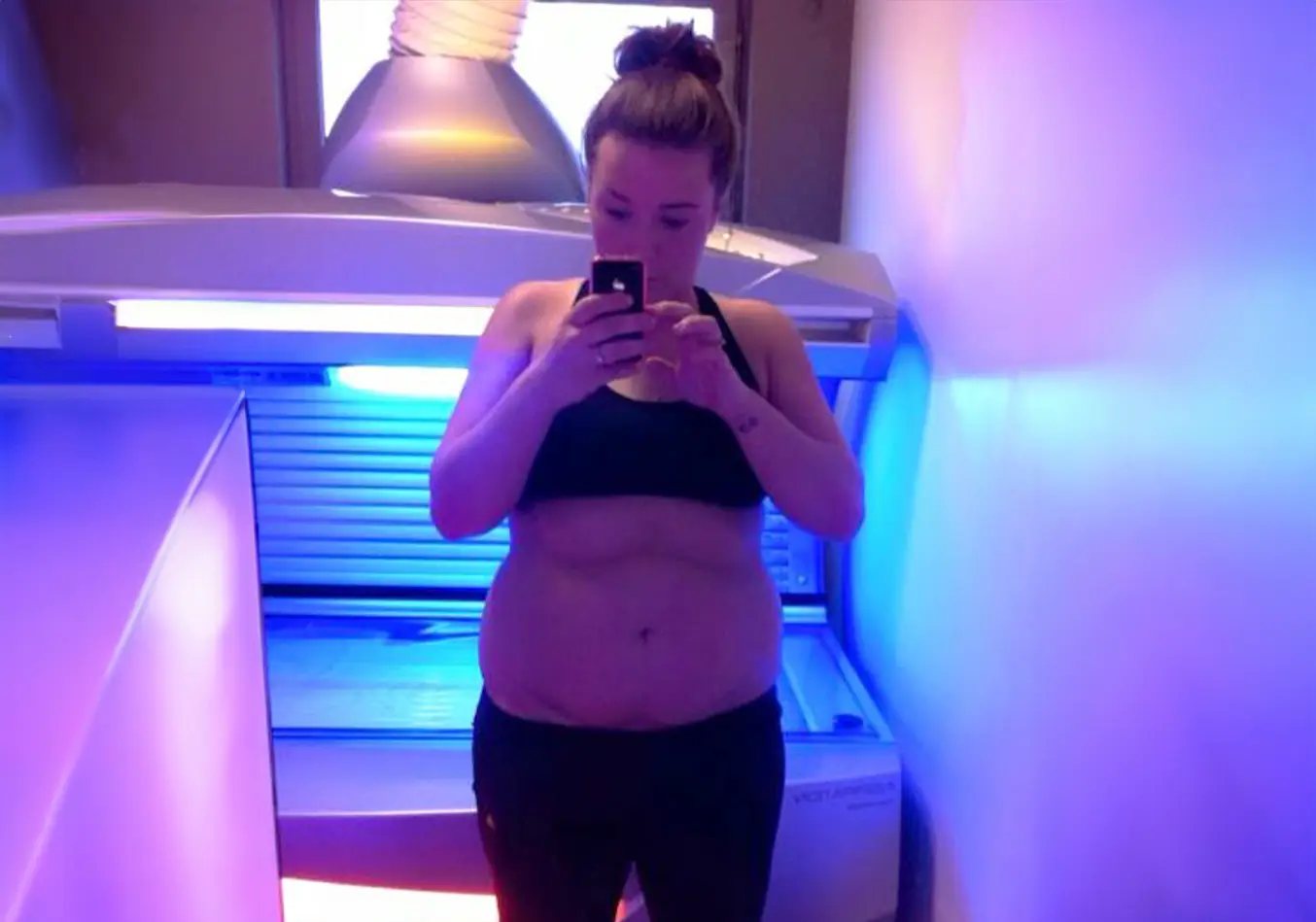 Anna Hahn steht in Sportkleidung vor einem Solarium und fotografiert sich – symbolisch für den Anfang ihrer Abnehmreise.