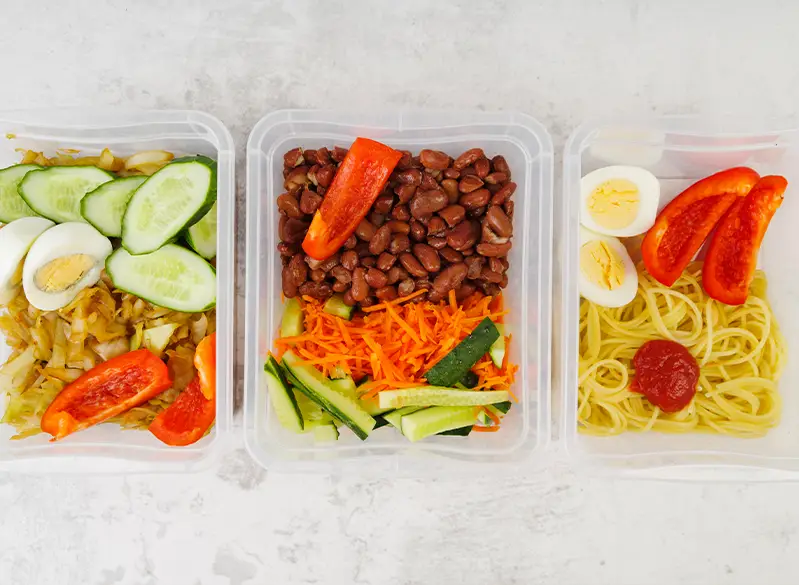 Drei ausgewogene Mahlzeiten im Meal-Prep-Stil mit Bohnen, Nudeln, Eiern, frischem Gemüse und Karotten – einfache Rezepte zum Vorbereiten.