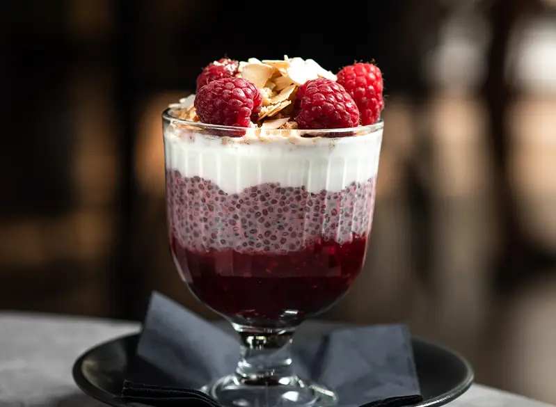 „Chia-Pudding mit Joghurt, Himbeeren, Mandelblättchen und Beerenschicht – gesundes Dessert oder Frühstück aus dem Anatomie Journal.