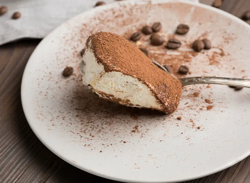 Löffel Tiramisu mit Kakaopulver und Kaffeebohnen – cremiges Dessert aus dem Anatomie Journal.