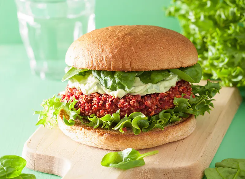 Vegetarischer Burger mit knusprigem Patty, Salat und cremiger Sauce auf Holzbrett – Anatomie Kitchen Around the World Rezept