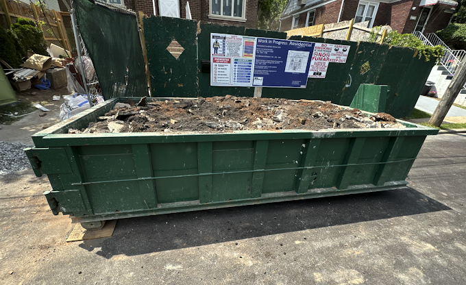 Ultimate Dumpsters Green construction dumpster filled with demolition debris on street. nationwide across the U.S.
